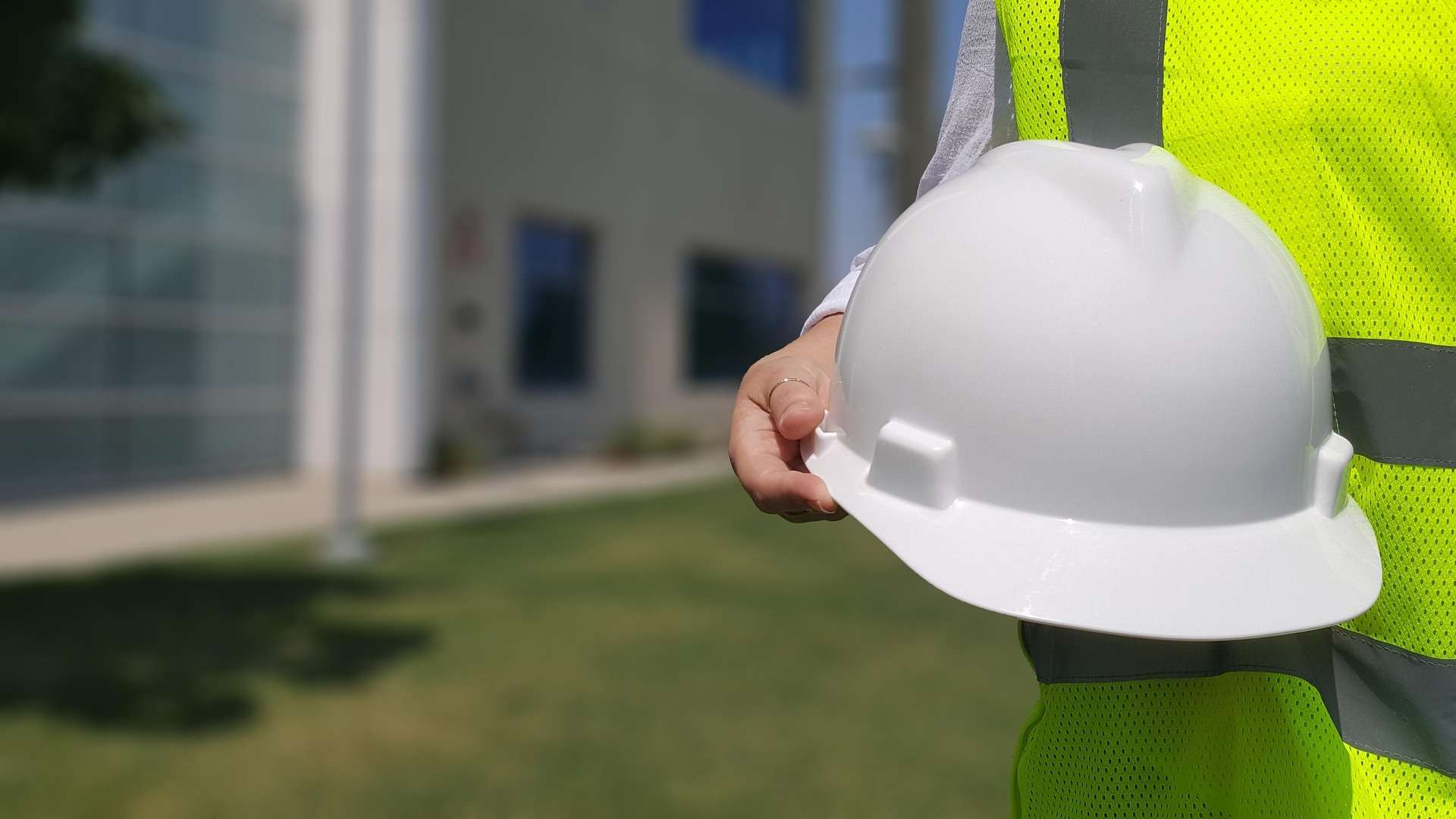 Casque de protection blanc tenu par un ouvrier en gilet haute visibilité